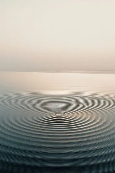 Ondas concéntricas en agua quieta al atardecer.