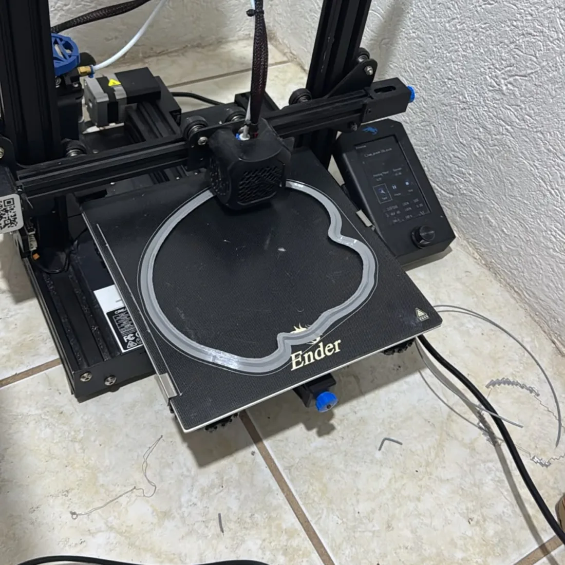 Ender 3 imprimiendo la primera capa: el contorno de Atmósfera dibujado sobre la cama.